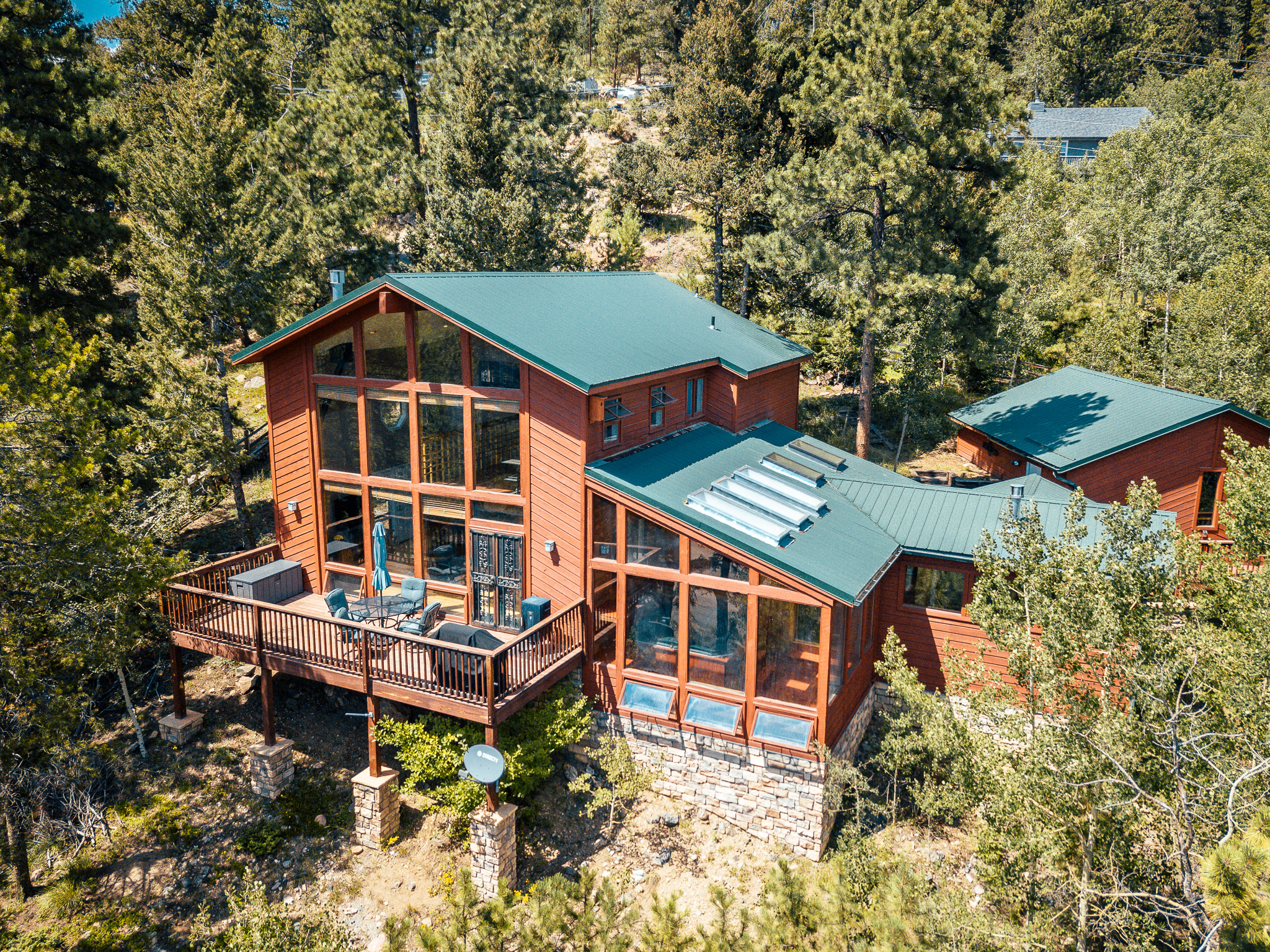 Aerial view of a wooded cabin with green roof